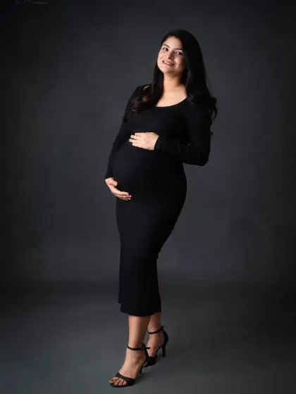 A full-length solo portrait in a classic black bodycon dress. This is a timeless and elegant way to document your pregnancy silhouette.
