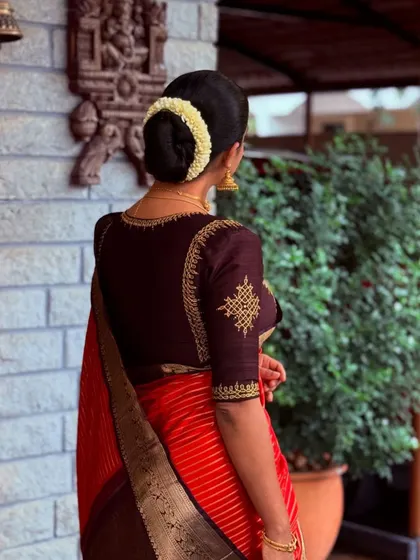 A back view showcasing the fit and finish of a custom-tailored blouse, complete with traditional hair adornments.