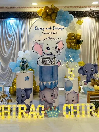 A cute elephant theme for a twins' fifth birthday party. The setup features a custom backdrop, themed plinths, and 'BABY' blocks.