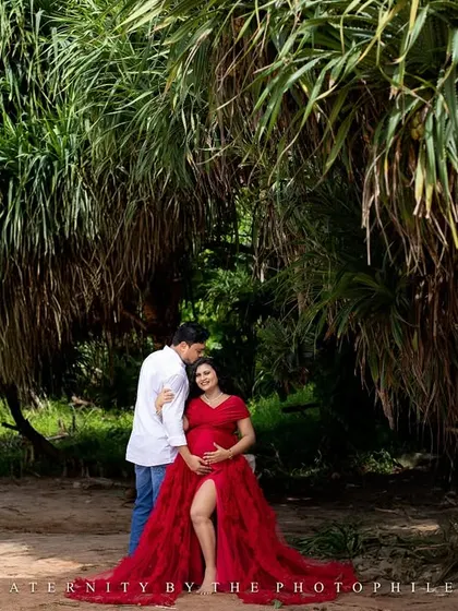 A stunning wide shot taken at Varkala Beach, with the unique cliffside greenery providing a lush contrast to the red gown and sandy shore.