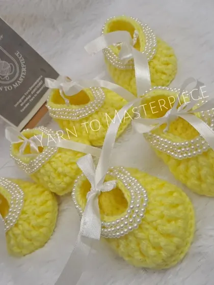 These bright yellow booties are decorated with a string of pearls and a white satin ribbon, making them a cheerful and elegant choice.