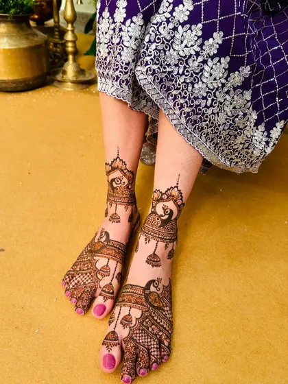 This design features elegant peacocks with hanging jhumka (earring) motifs, creating a delicate and decorative look for the bride's feet.