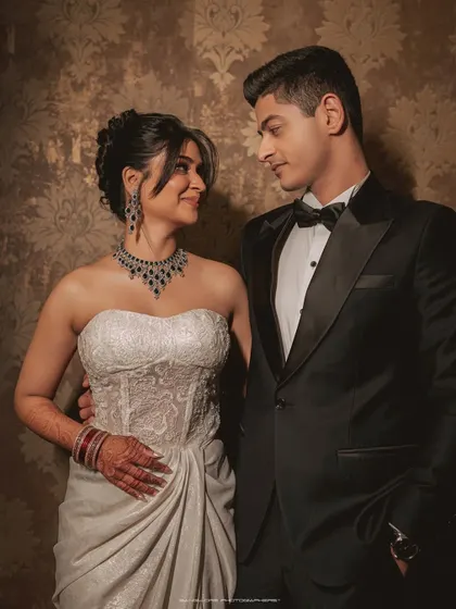A classic portrait that radiates elegance. The groom's smart tuxedo and the bride's modern white gown create a beautiful contrast, perfect for a sophisticated reception look.