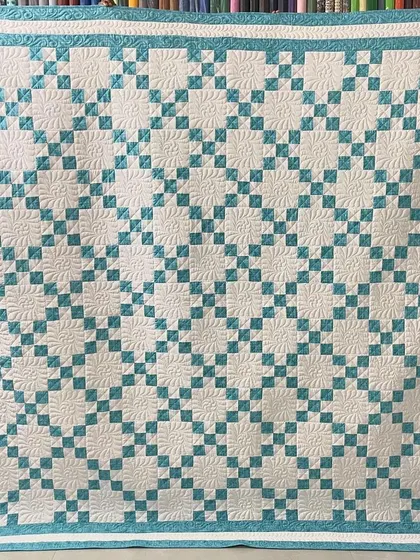 A fresh and clean "9-Patch" quilt in white and teal. The simple pattern is elevated by the intricate, custom longarm quilting.