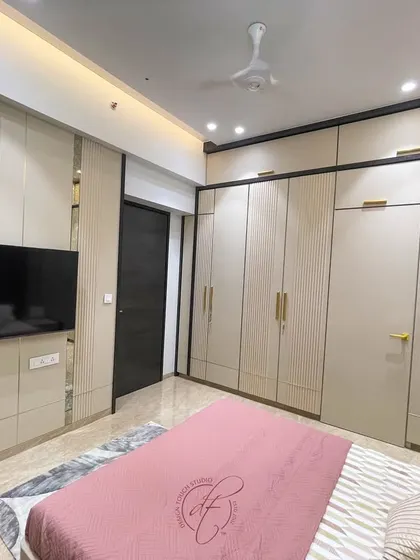 This shot showcases the full wall of custom wardrobes with elegant gold handles. The design provides ample storage while serving as a stylish architectural element in the room.