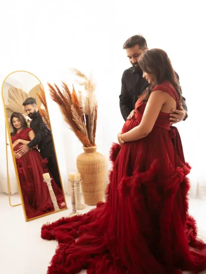 Using mirrors adds a layer of depth and reflection to your portraits. This creative shot in a flowing red gown captures both the expecting mother and her beautiful reflection, creating an elegant and thoughtful image.