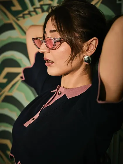 A chic profile shot that highlights the retro-cool vibe of the tinted sunglasses and the clean lines of the outfit.