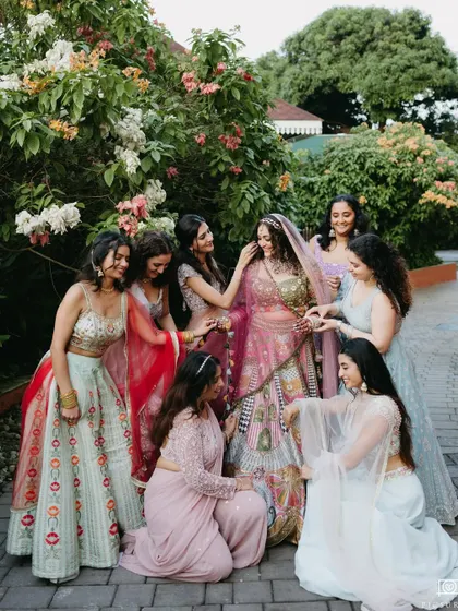 The bride shares a beautiful, candid moment with her bridesmaids in a garden setting, their interactions full of warmth and friendship, showcasing the importance of loved ones.