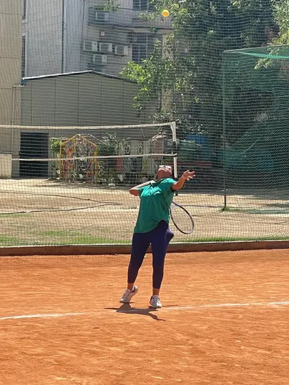 A female player practicing her serve on the clay court. We provide a supportive environment for our female athletes to thrive.