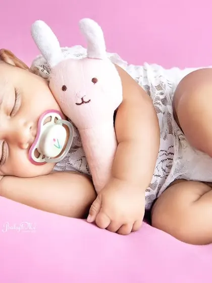 This sleeping angel is cuddling her little bunny, looking so peaceful on a soft pink background. Simple setups like this are perfect for highlighting your baby's natural sweetness.