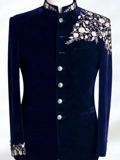 A deep blue velvet Jodhpuri jacket with delicate silver floral embroidery on the shoulder. The combination of velvet and intricate work is pure elegance.