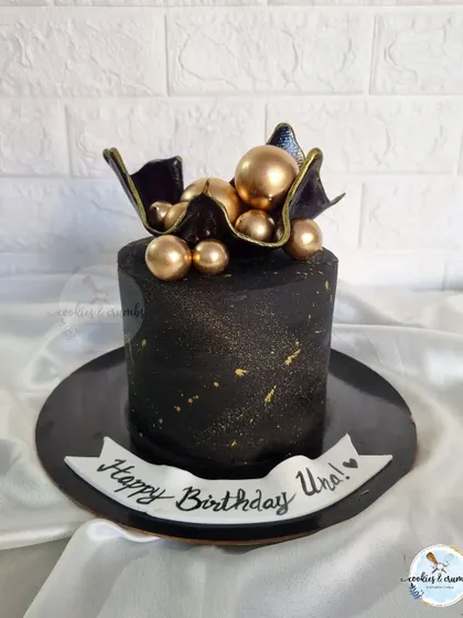 One of my favorite black cakes. This design features a black chocolate sail topper and gold spheres, creating a dramatic and artistic look.
