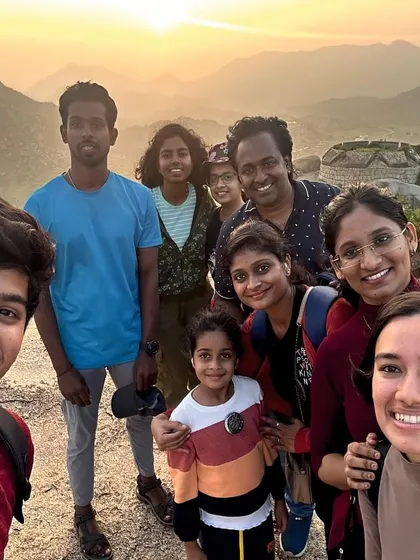 A happy group selfie from a hilltop, capturing the joy of reaching the summit together on a day trek.