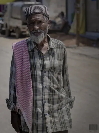 A portrait of an elderly man on the street. His direct gaze and the details of his clothing tell a story of a long life lived.