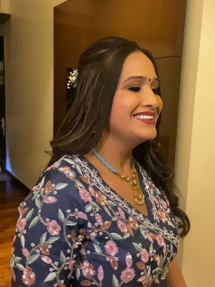 A joyful wedding guest showing off her subtle glam makeup. The bright red lip perfectly complements her smile and her festive blue outfit.