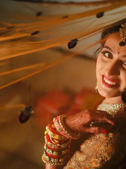 A classic shot of the bride looking through her veil. The warm lighting enhances the golden tones in her makeup and the richness of her attire.