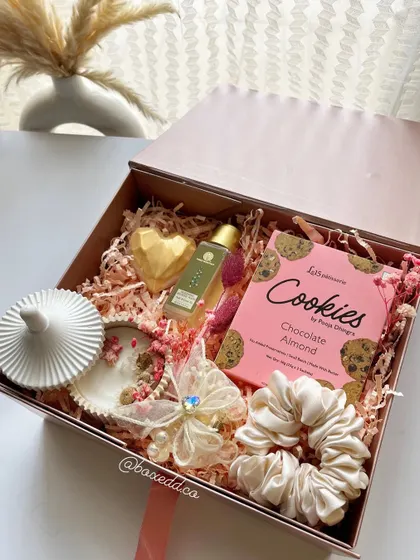 We love creating color-coded gifts. This pink-themed hamper shows how we coordinate every item, from the cookies and candle to the scrunchie and bath soap, for a visually stunning and cohesive gift box.