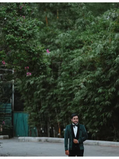 A handsome portrait of the groom in his reception tuxedo, standing against a lush bamboo background.