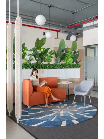 The same breakout space, showing how it feels to be seated and working or reading. The hanging globe lights add a soft, ambient glow, making the area feel cozy and distinct from the main work floor.