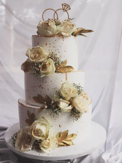 Another look at this classic three-tier wedding cake, highlighting the beautiful texture of the roses and gold details.
