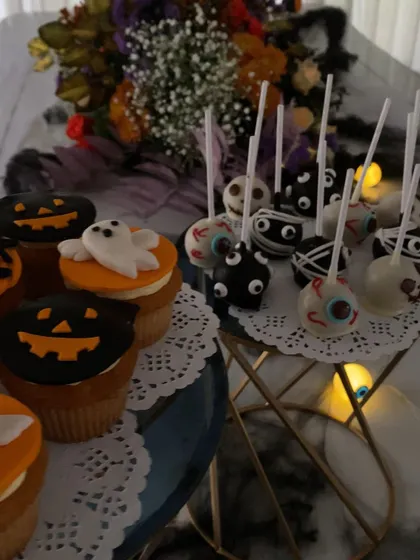 A close-up of the spooky treats at a Halloween party. The cake pops are decorated to look like eyeballs and mummies, showcasing the creative and thematic food options I can arrange.