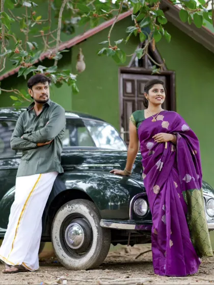 A classic, vintage-themed pre-wedding shot with an old-fashioned car. The couple is dressed in traditional South Indian attire, creating a timeless and elegant photograph.