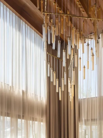 This cascading glass chandelier in the House of Terraces was chosen to complement the double-height, barrel-vaulted wooden ceiling, adding a touch of modern glamour to the rustic warmth of the wood.