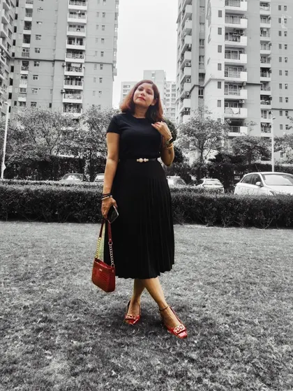 A classic all-black pleated skirt and top, accented with a pop of red from my bag and shoes. The black and white filter on the background makes the colors stand out.