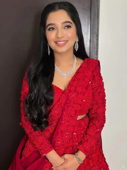 A full-length view of the Sangeet look, showing how the soft glam makeup complements the bold red ensemble.