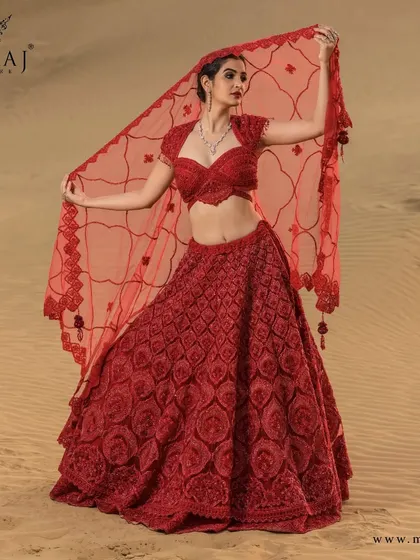 A ravishing red netted crop top lehenga. This piece is exquisitely handwoven with a scallop design and embellished with red thread embroidery, sequins, and stonework for a truly gorgeous look.