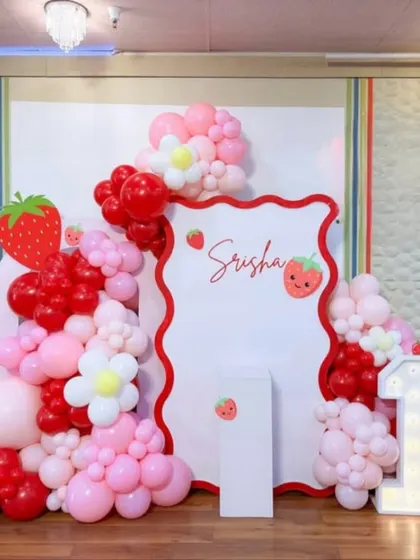 Srisha's "Berry First Birthday" was a sweet treat. This setup features a custom-shaped backdrop with red and pink balloons, strawberry cutouts, and daisy accents.