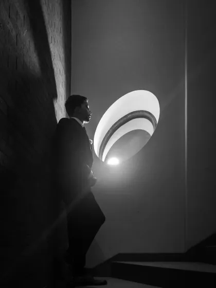 A solitary, dramatic groom portrait in black and white. The creative use of light and shadow creates a powerful, cinematic image.