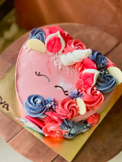 A close-up of the heart-shaped unicorn cake, showing the sleepy eyes and colorful buttercream mane.