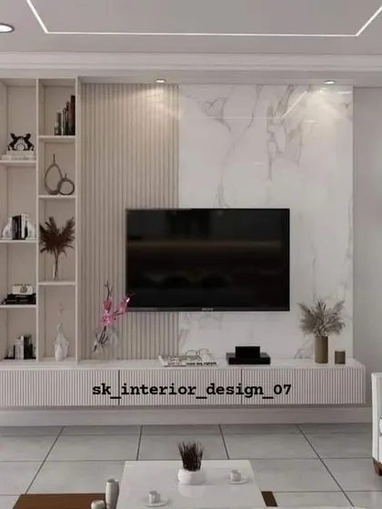 A bright and airy living room featuring a TV unit with a white marble backdrop and integrated shelving. The clean lines and light colors make the space feel open and spacious.