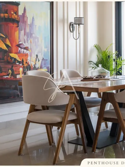 In the dining area, a vibrant painting adds a splash of color to the neutral palette. The modern dining chairs and simple table are chosen to complement the art and maintain a sense of uncluttered elegance.