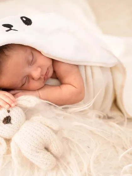 A cozy, hooded blanket with a cute bear face makes for an adorable and simple portrait, keeping the focus on the baby's peaceful sleep.