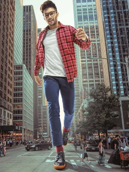 A playful, surrealist concept for a menswear editorial, styling a casual look of a plaid shirt and jeans on a model of gigantic proportions. This creates a fun, high-impact visual for a commercial campaign.