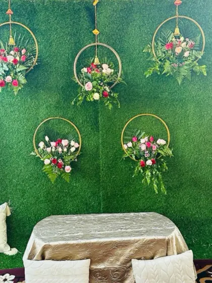 A simple and elegant Mehendi seating arrangement. The backdrop is an artificial green wall decorated with beautiful floral hoops.