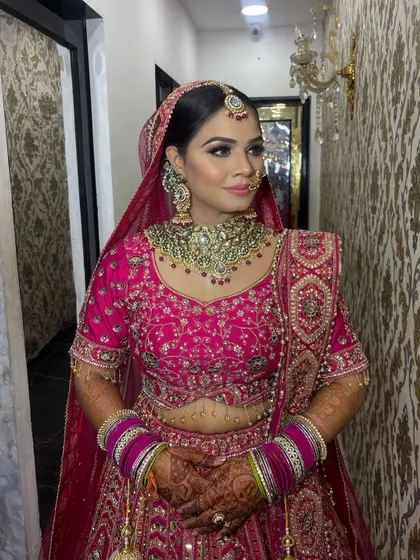 This bride radiates confidence in her pink wedding attire. The makeup features a defined contour and sharp winged eyeliner, balanced with a neutral lip color to keep the focus on her eyes.