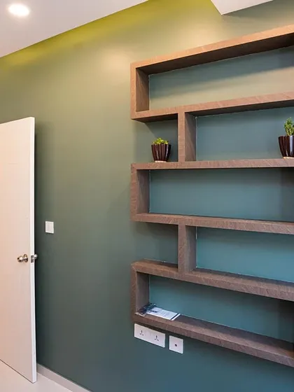 A custom-designed geometric open-shelf unit mounted on a green accent wall. This serves as a creative and functional way to display decor and small plants.