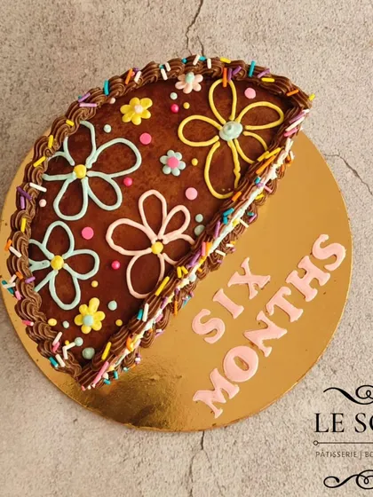 This semi-circle cake is a fun way to mark six months. It's a half-kg Chocolate Caramel cake decorated in a Magnolia-bakery style with rich chocolate buttercream and colorful floral piping.