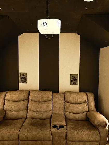 A head-on view of the recliners, with the front speakers visible on the wall. The black and white acoustic panels create a simple yet effective design.
