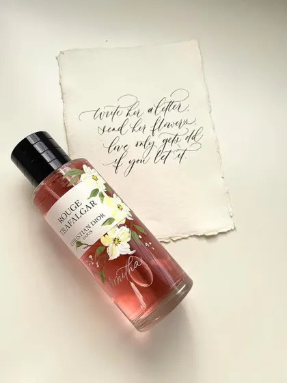This image showcases how I combine multiple art forms: hand-painting florals on a perfume bottle, engraving a name directly onto the glass, and creating a matching handwritten calligraphy note. It's the ultimate personalized gift.