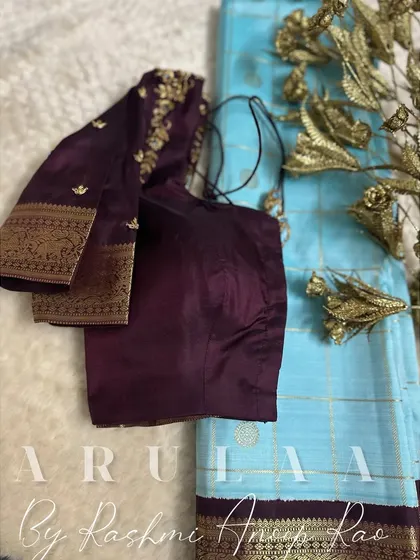 The full view of the wine-colored blouse and light blue saree combination. A beautiful contrast that works wonderfully.