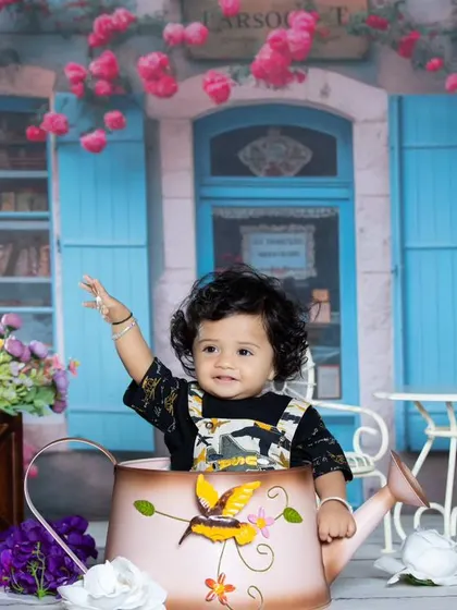 This little one is waving from her watering can perch, enjoying the beautiful floral scenery.