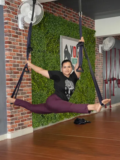 Using an aerial yoga setup to practice Samakonasana (middle splits), allowing gravity to help deepen the stretch.