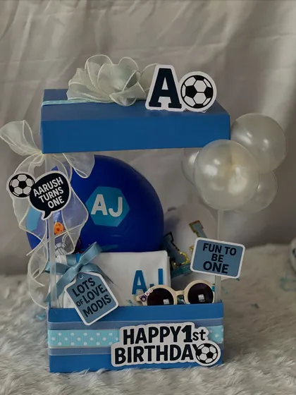 The complete football-themed hamper for Aarush's first birthday. The two-tiered blue box is filled with sporty goodies and decorated with fun 'Happy 1st Birthday' and 'Fun to be One' signs.