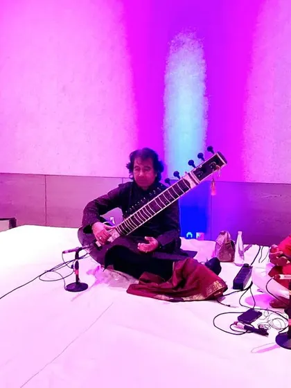 A performance shot with Ustad Rafique Khan and Sarfaraaz Khan under purple lighting.