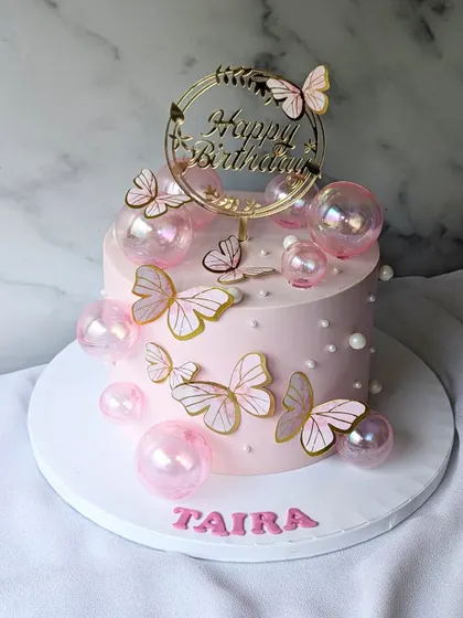A pretty cake in pink, decorated with butterflies and iridescent bubbles. It's a simple yet magical design for a special birthday.