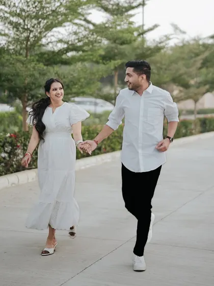 A candid and energetic shot of a couple running and laughing, capturing the pure joy of their pre-wedding moments.